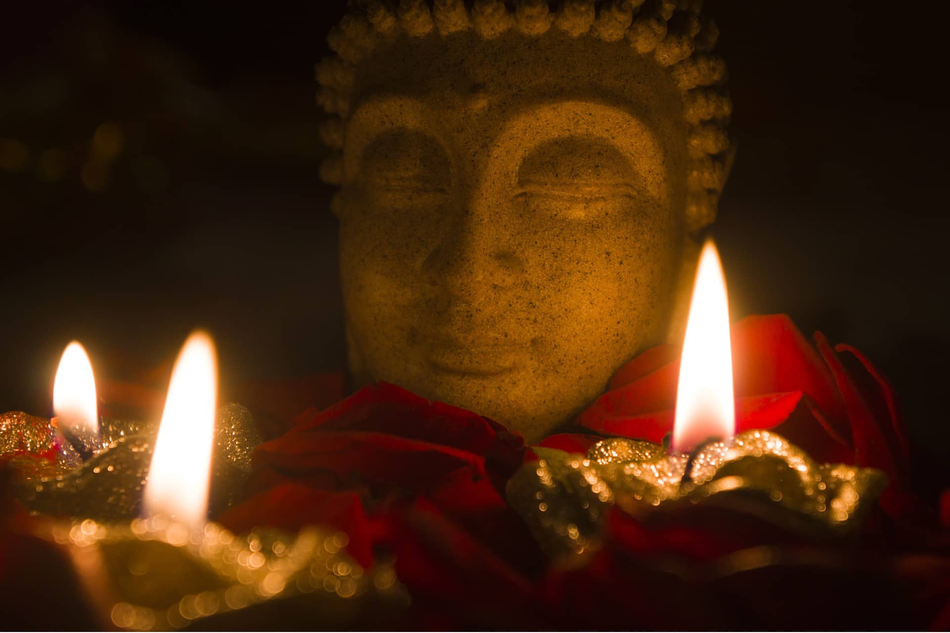 Kopf einer Buddha-Statue mit Kerzen davor